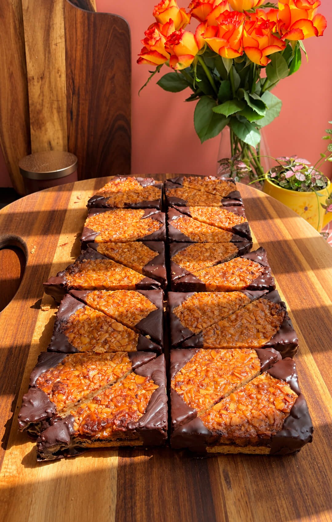 Homemade German nut corners arranged on a wooden board with golden almond walnut topping and dark chocolate dipped corners.