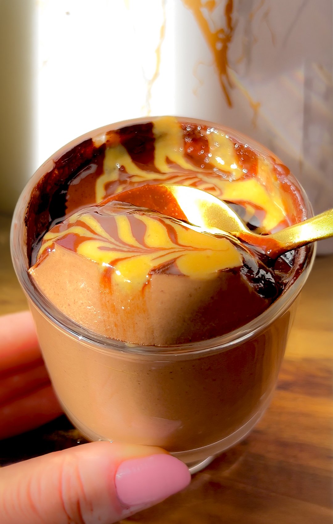 Close-up of thick, creamy chocolate Greek yogurt pudding with a glossy chocolate peanut butter swirl and spoon.