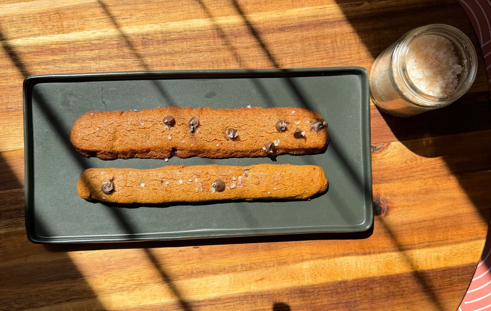 Golden and deeper-brown chocolate chip cookie fries served with raspberry jam, chocolate sauce and raspberry cream dip, showing different shapes and baked finishes.