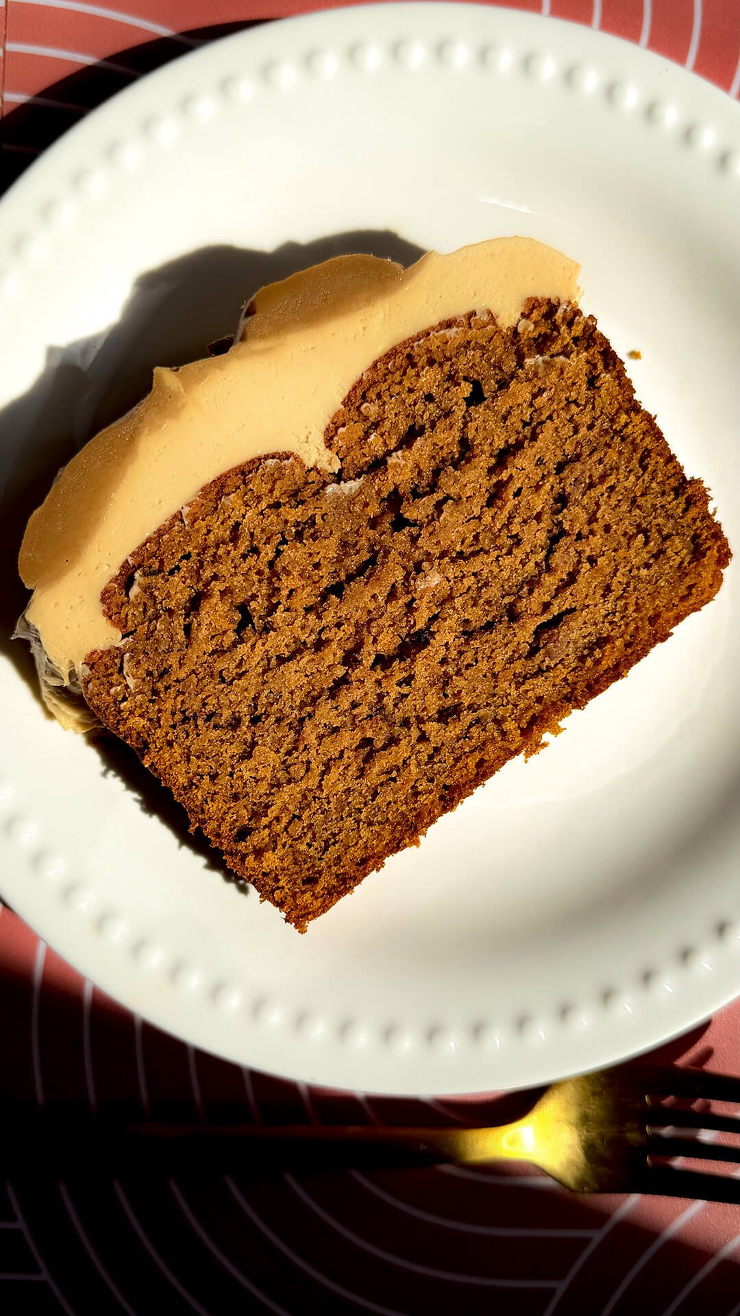 A thick slice of healthy pumpkin bread on a white plate, showing its tender crumb and thick, silky peanut butter cream cheese frosting. This easy gluten-free, refined sugar-free loaf uses almond, oat, and lupin flours, coconut sugar, and brown monk fruit sweetener, with a sugar-free option.