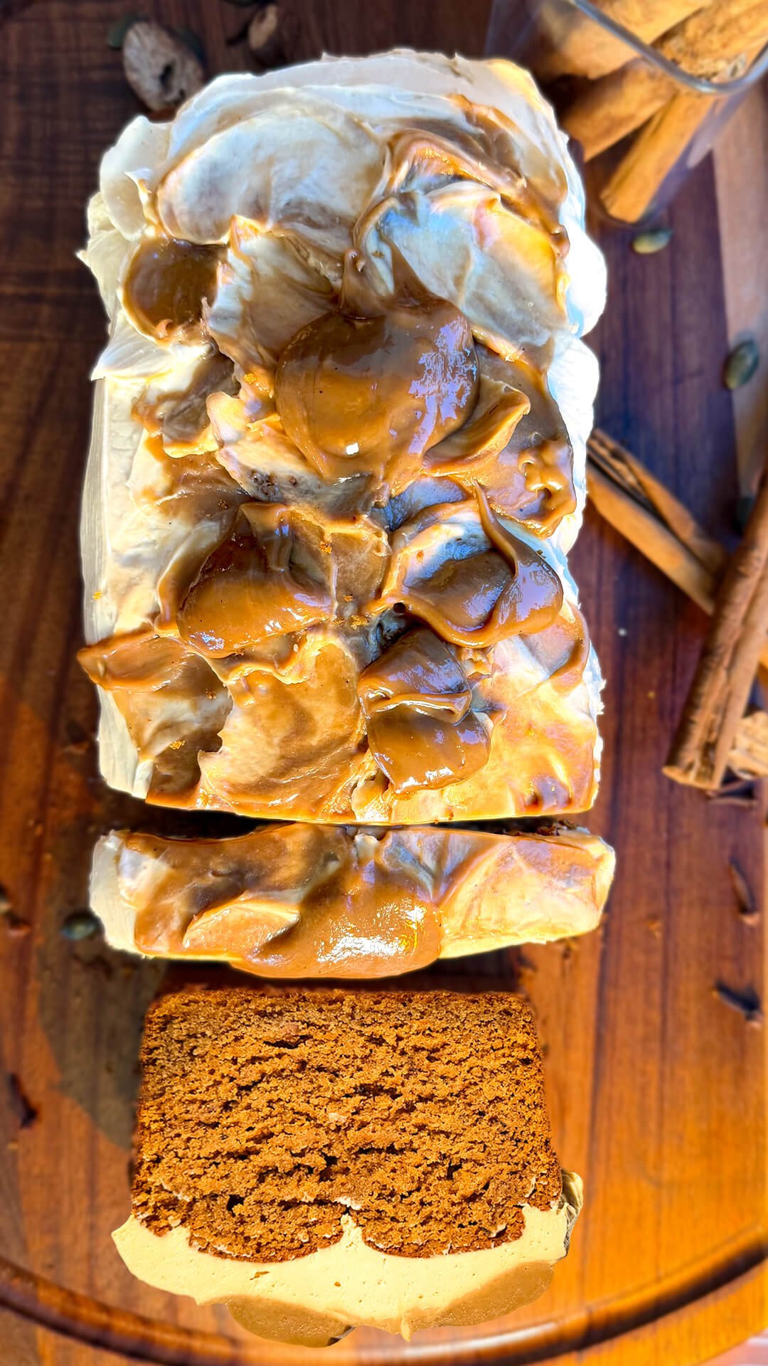 Overhead view of healthy pumpkin bread with thick slices, silky peanut butter cream cheese frosting, and homemade coconut caramel on a wooden board. This easy gluten-free, refined sugar-free loaf uses almond, oat, and lupin flours, coconut sugar, and brown monk fruit sweetener, with a sugar-free option.