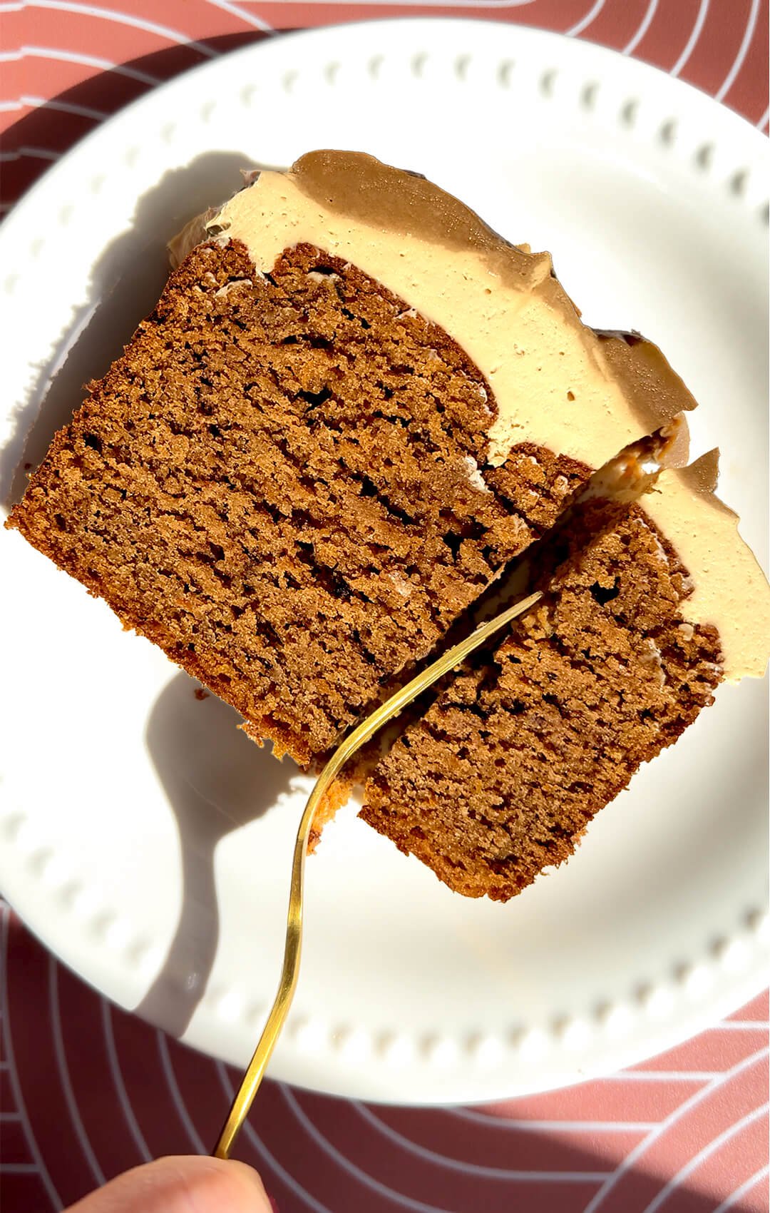 A gold fork cuts into a thick slice of healthy pumpkin bread topped with creamy peanut butter cream cheese frosting. The moist gluten-free, refined sugar-free loaf combines almond, oat, and lupin flours with coconut sugar and brown monk fruit sweetener in an easy recipe with a sugar-free option.