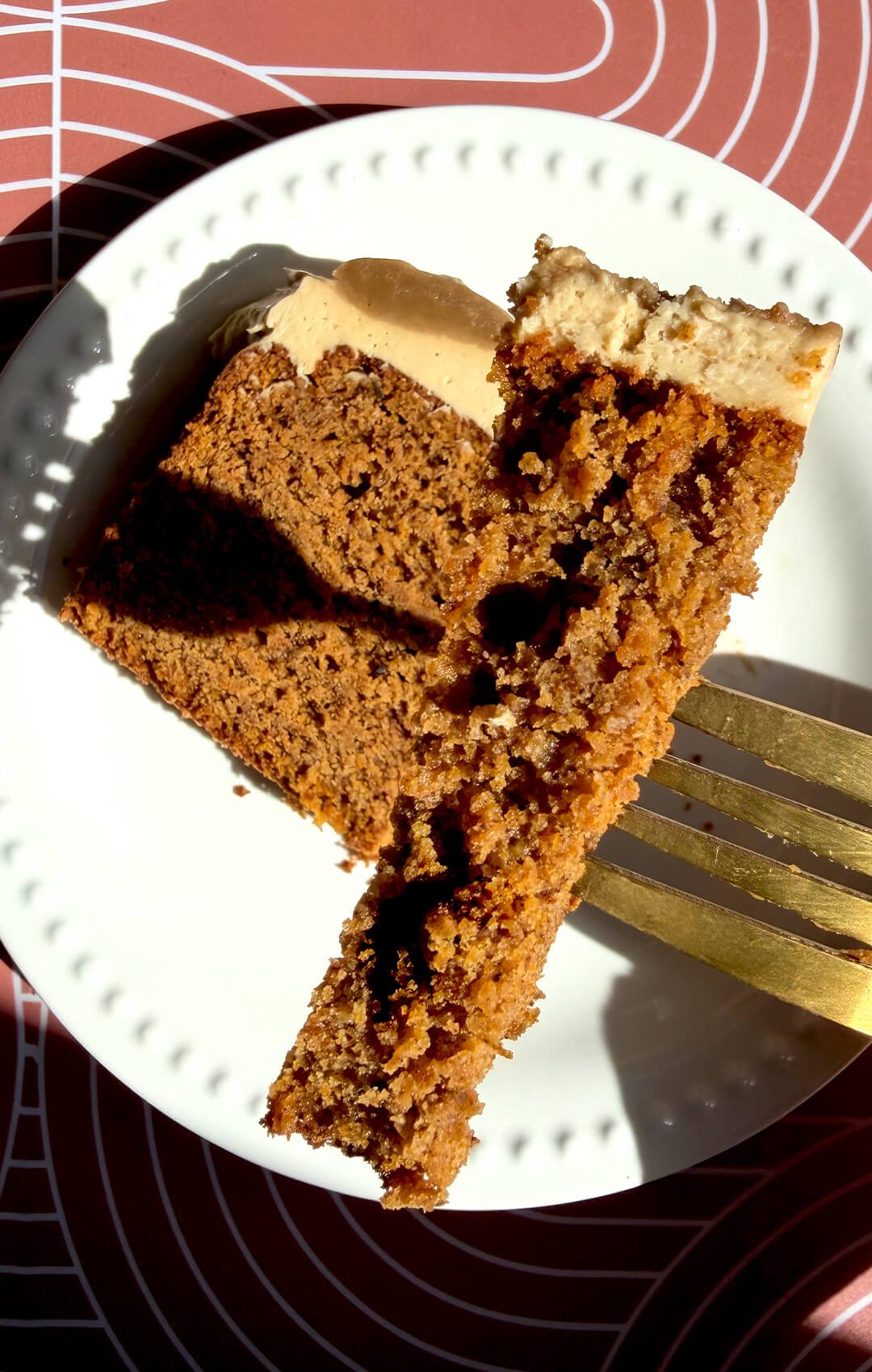 A fork holds a tender bite of healthy pumpkin bread beside a frosted slice, showing how beautifully its moist crumb holds together. This easy gluten-free, refined sugar-free recipe uses almond, oat, and lupin flours, coconut sugar, and brown monk fruit sweetener, with a sugar-free option.