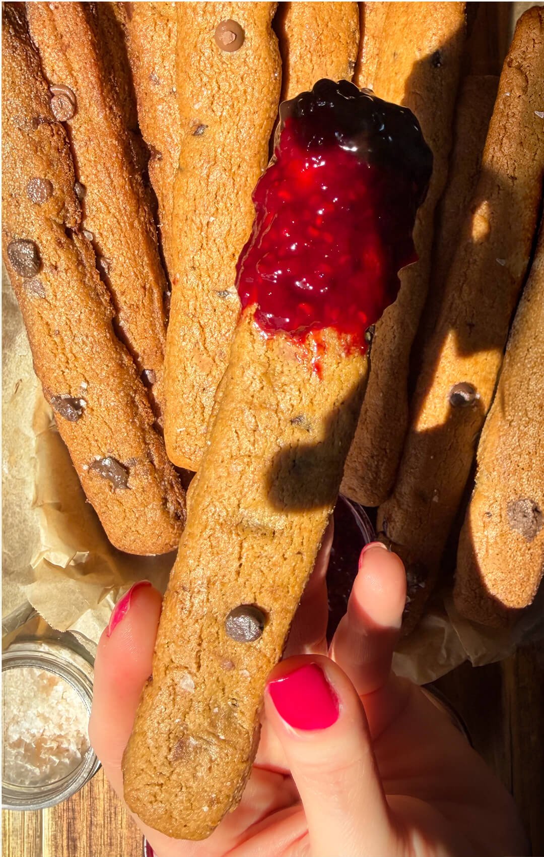 Two homemade chocolate chip cookie fries side by side on a plate, one wider with more chocolate chips and the other slimmer, showing different shapes for baking.